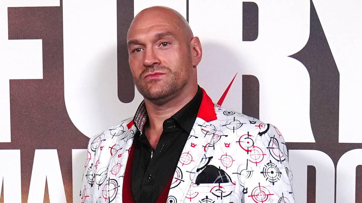 Tyson Fury w kolorowym garniturze na tle plakatu z napisem "FURY MACHMUDOV"