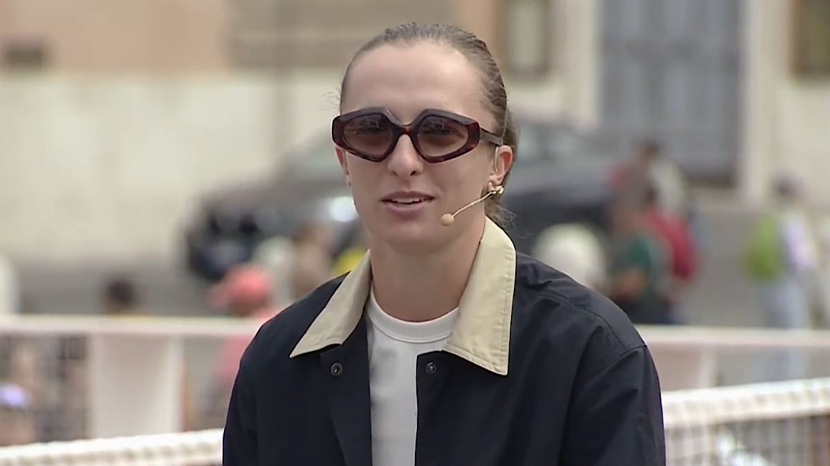 Kobieta w okularach przeciwsłonecznych i ciemnej kurtce z mikrofonem.
