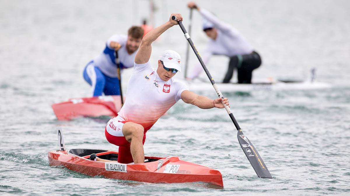 Polski kajakarz wiosłuje w czerwonej łodzi podczas zawodów.