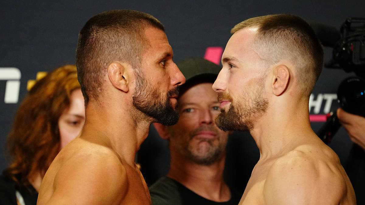 Dwóch zawodników MMA, Mateusz Gamrot i jego rywal, stoją twarzą w twarz, intensywnie patrząc na siebie.