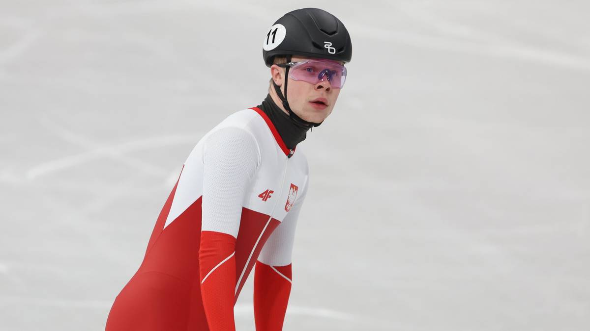 Polski panczenista w czerwono-białym stroju i kasku na lodowisku.