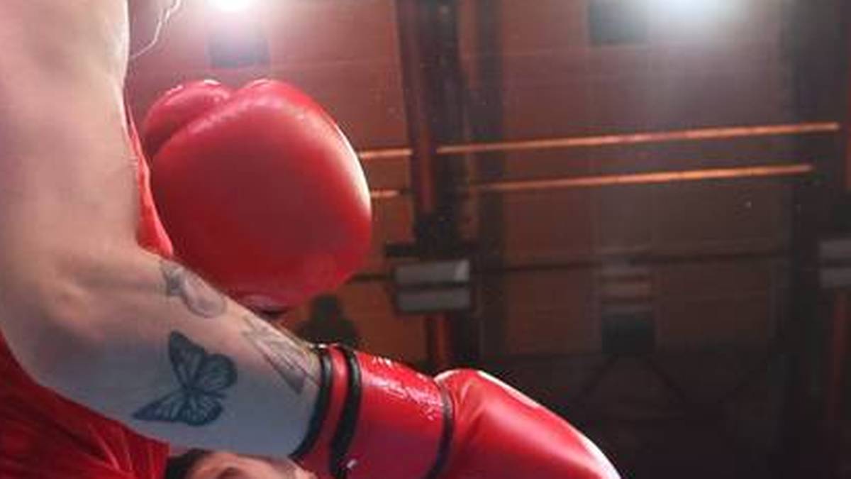 Zbliżenie na rękę boksera w czerwonej rękawicy, z tatuażem motyla na przedramieniu.