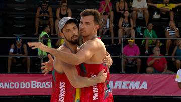 Dw&oacute;ch mężczyzn w strojach sportowych przytulających się po meczu siatk&oacute;wki plażowej.