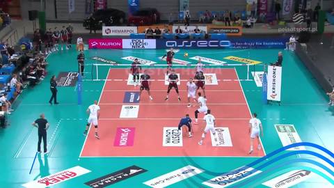 Mecz siatk&oacute;wki z udziałem zawodnik&oacute;w w białych i czerwonych strojach na pomarańczowym boisku.