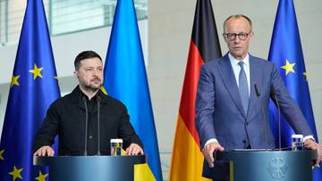 Dw&oacute;ch mężczyzn stoi za podium, przed nimi flagi Ukrainy i Unii Europejskiej.