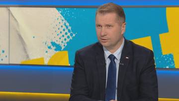 Mężczyzna w garniturze i krawacie wypowiada się w studio telewizyjnym