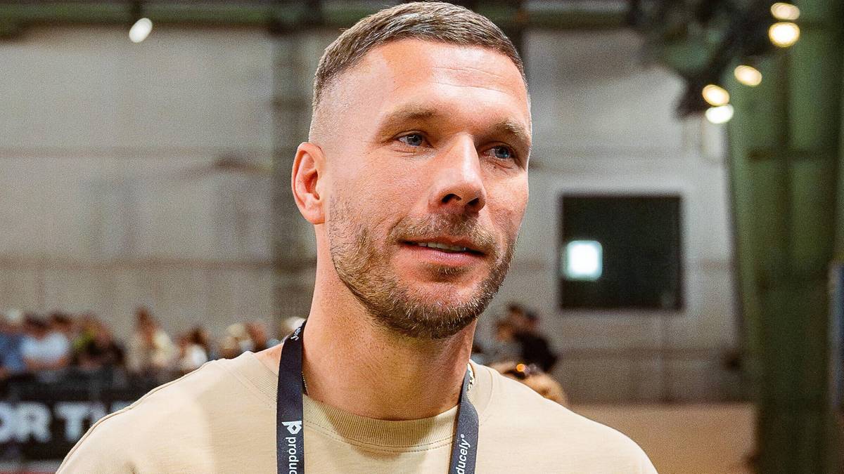 Portret mężczyzny, zawodnika piłki nożnej Lukasa Podolskiego, na szyi ma założoną identyfikacyjną smycz.