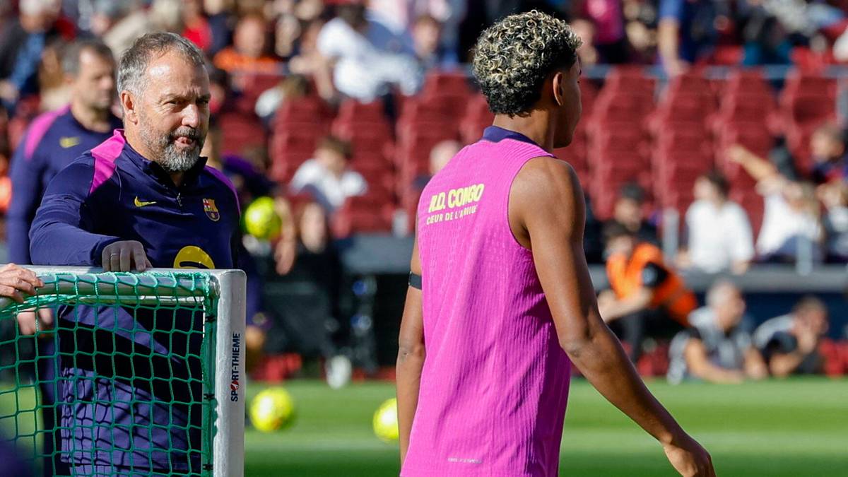 Lamine Yamal w różowej kamizelce treningowej i trener na murawie stadionu