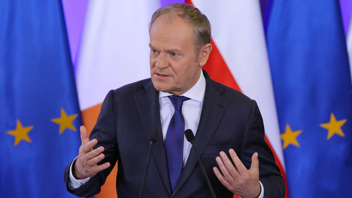 Donald Tusk przemawia na tle flag Unii Europejskiej i Polski.