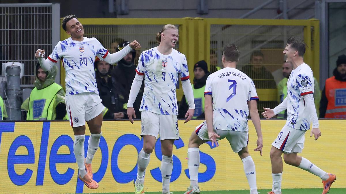 Czterech piłkarzy w białych strojach z niebieskimi wzorami świętuje zdobycie bramki.