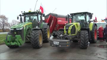 Dwa nowoczesne ciągniki rolnicze, jeden zielony John Deere, drugi jasnozielony Claas, stoją obok siebie na drodze. W tle czerwona przyczepa i polska flaga.