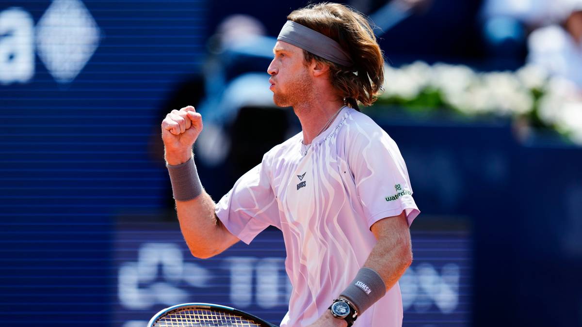 Tenisista z opaską na głowie, w białej koszulce, świętuje zdobycie punktu, zaciskając pięść.