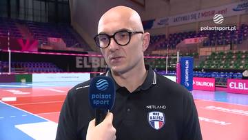 Mężczyzna w okularach i czarnej koszulce z logo "NETLAND MKS KALLISZ" udziela wywiadu przed mikrofonem Polsat Sport.