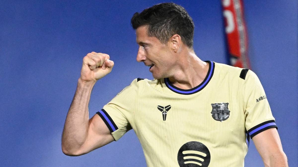 Piłkarz w ż&oacute;łtej koszulce FC Barcelony z dumą unosi pięść w geście zwycięstwa.