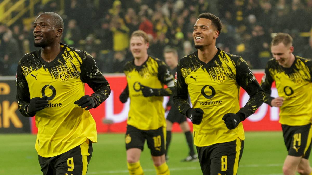 Piłkarze Borussii Dortmund w ż&oacute;łtych strojach biegają po boisku, jeden z nich cieszy się z bramki.