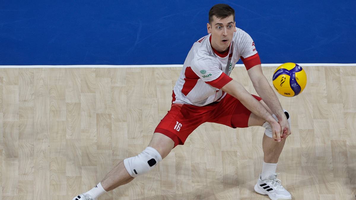 Siatkarz w czerwono-białym stroju z numerem 16 na koszulce przyjmuje piłkę w locie na drewnianej hali sportowej.