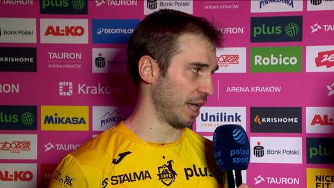 Mężczyzna w ż&oacute;łtej koszulce z logo STALMA udziela wywiadu z mikrofonem w ręku. W tle ściana z logotypami sponsor&oacute;w.