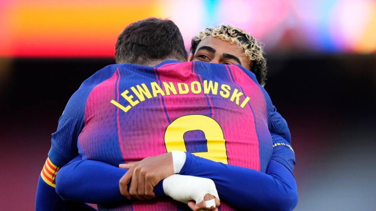 Piłkarze FC Barcelony, Robert Lewandowski i inny zawodnik, przytulają się na boisku.