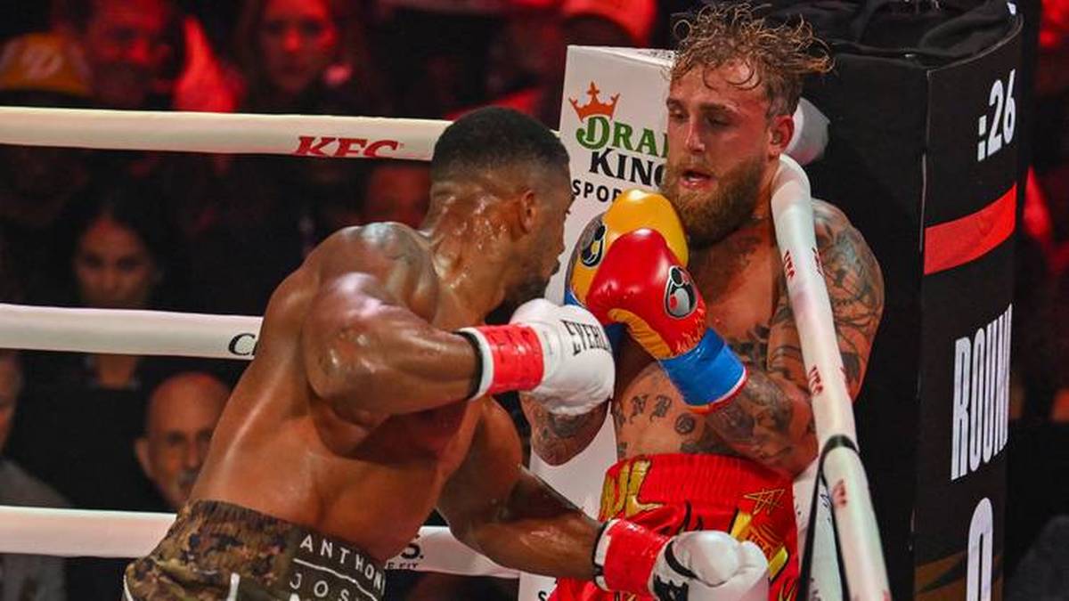 Dw&oacute;ch bokser&oacute;w w ringu podczas walki. Jeden z nich, Joshua, wyprowadza cios.