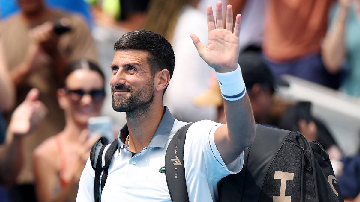Novak Djoković macha do publiczności podczas meczu tenisowego.