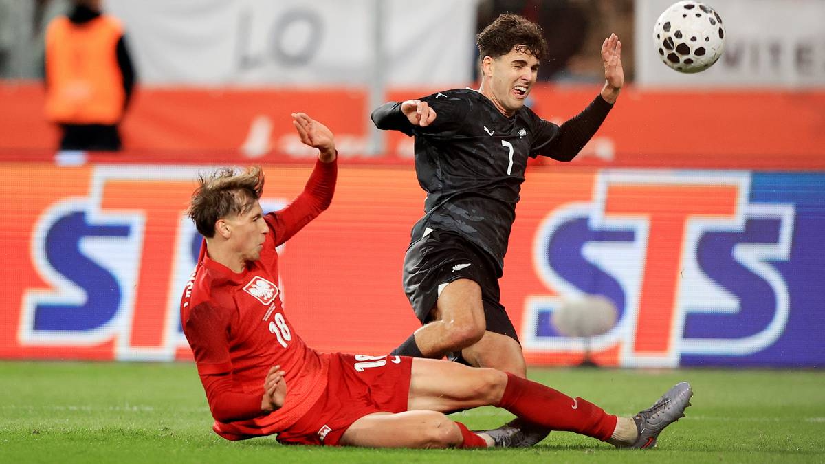 Dwóch piłkarzy walczy o piłkę w akcji podczas meczu.