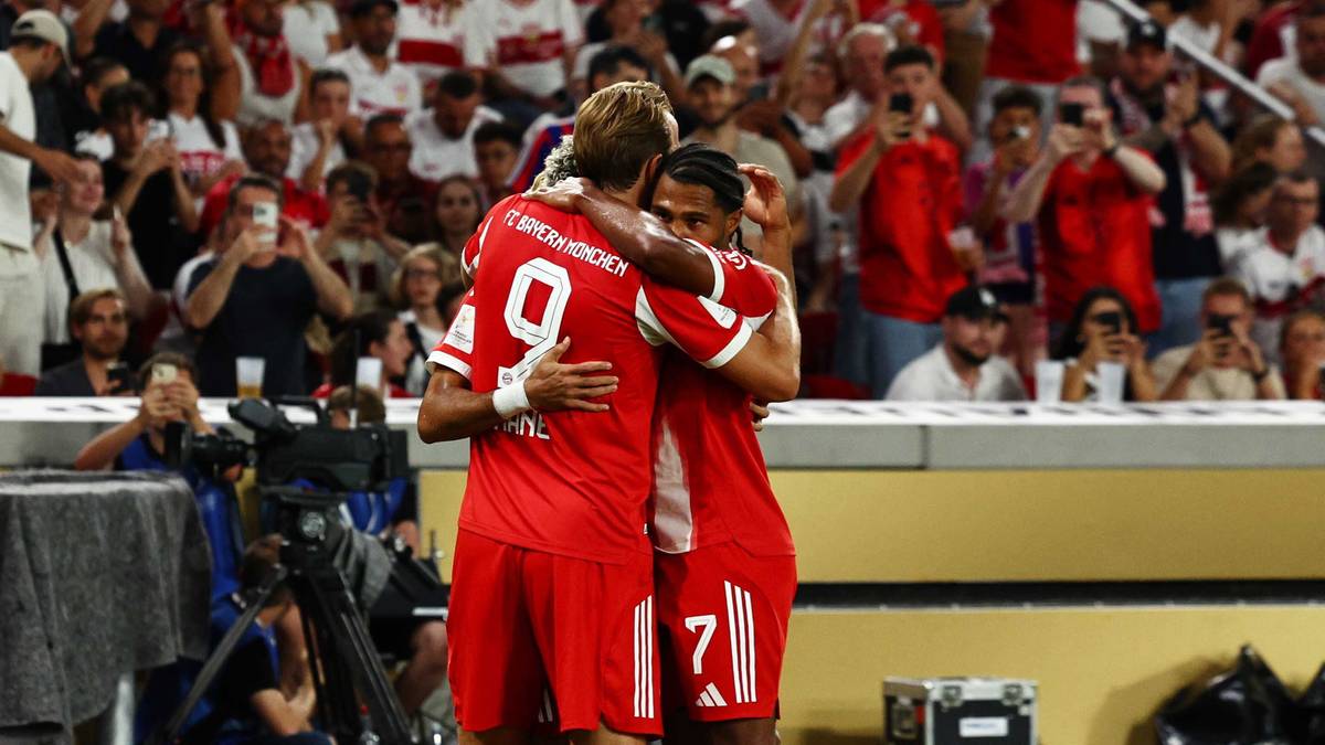 Dwóch piłkarzy w czerwonych strojach obejmuje się w geście radości na tle trybun kibiców.