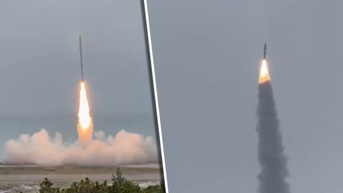 Trójstopniowa rakieta suborbitalna startuje, unosząc się w powietrze z płomieniem i smugą dymu.