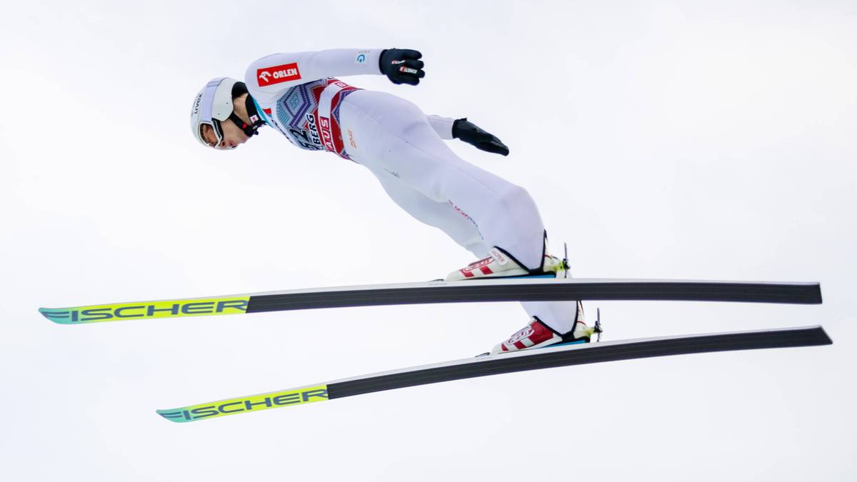 Skoczek narciarski w locie na nartach na tle g&oacute;r.