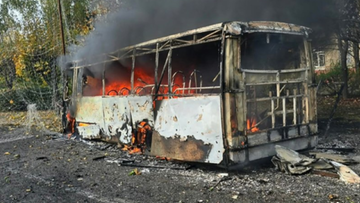 Wypalony i płonący autobus spowity gęstymi kłębami czarnego dymu.