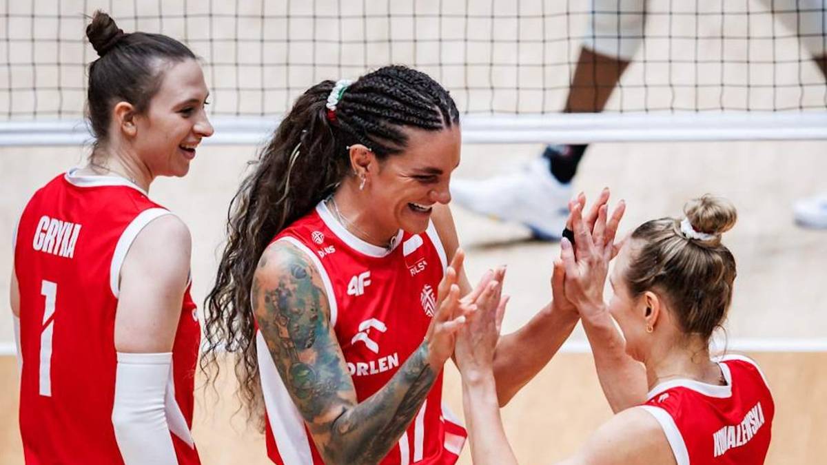 Trzy siatkarki w czerwonych strojach sportowych świętują po meczu, klaszcząc sobie nawzajem.