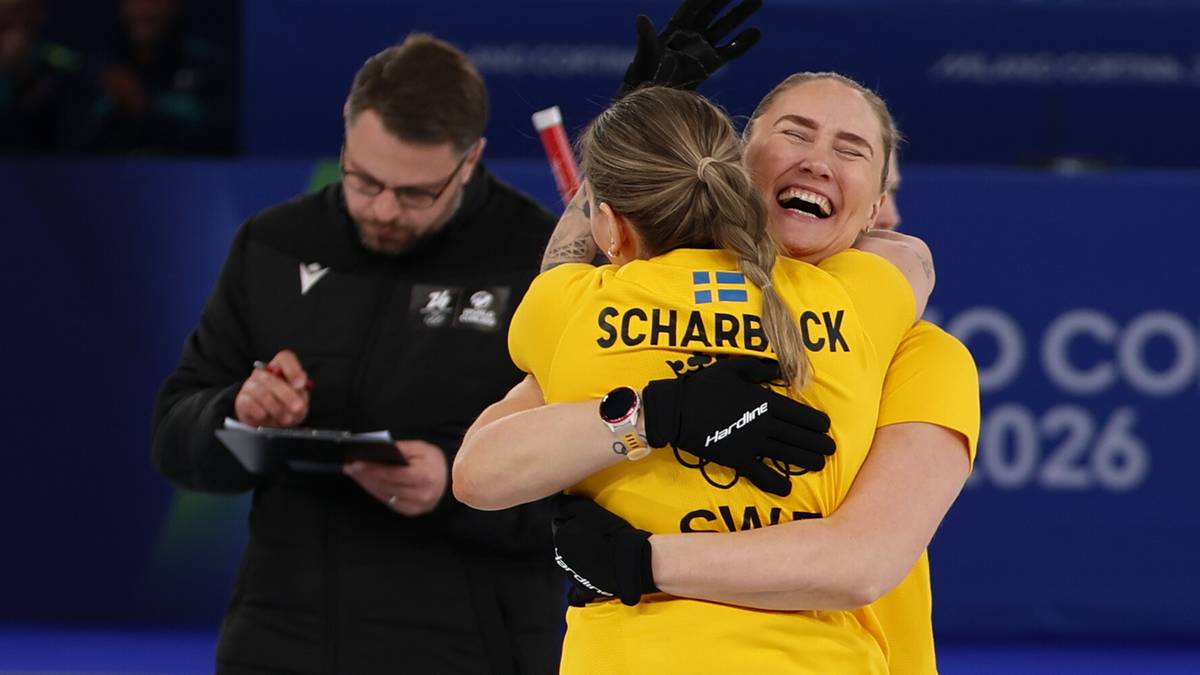 Trzy osoby w strojach sportowych, dwie kobiety obejmują się z radością, mężczyzna z tabletem obserwuje