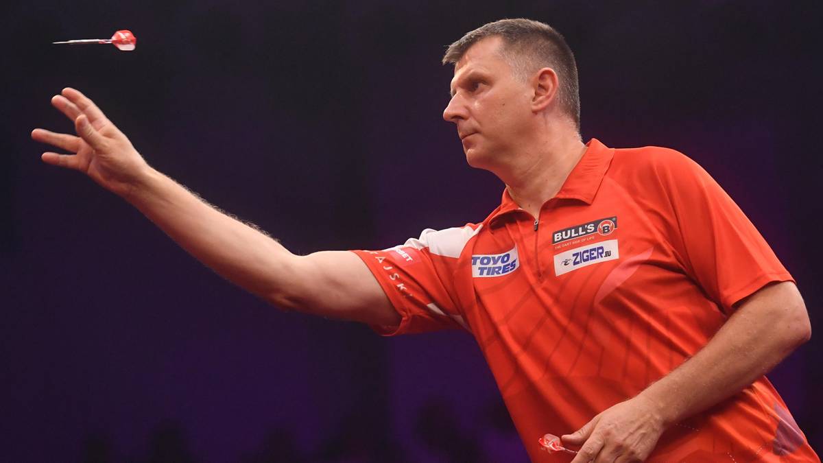 Mężczyzna w koszulce sportowej rzuca lotką do celu.