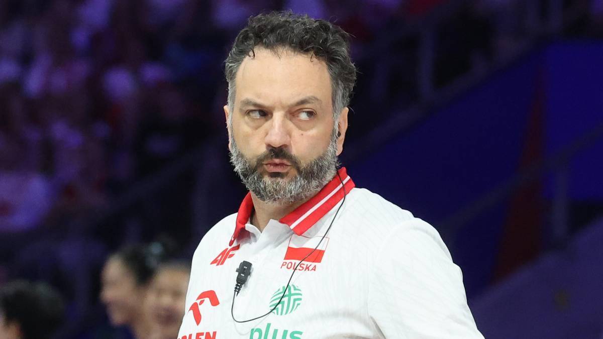 Portret mężczyzny z brodą, ubranego w białą koszulkę polo z logotypami reprezentacji Polski w siatkówce.