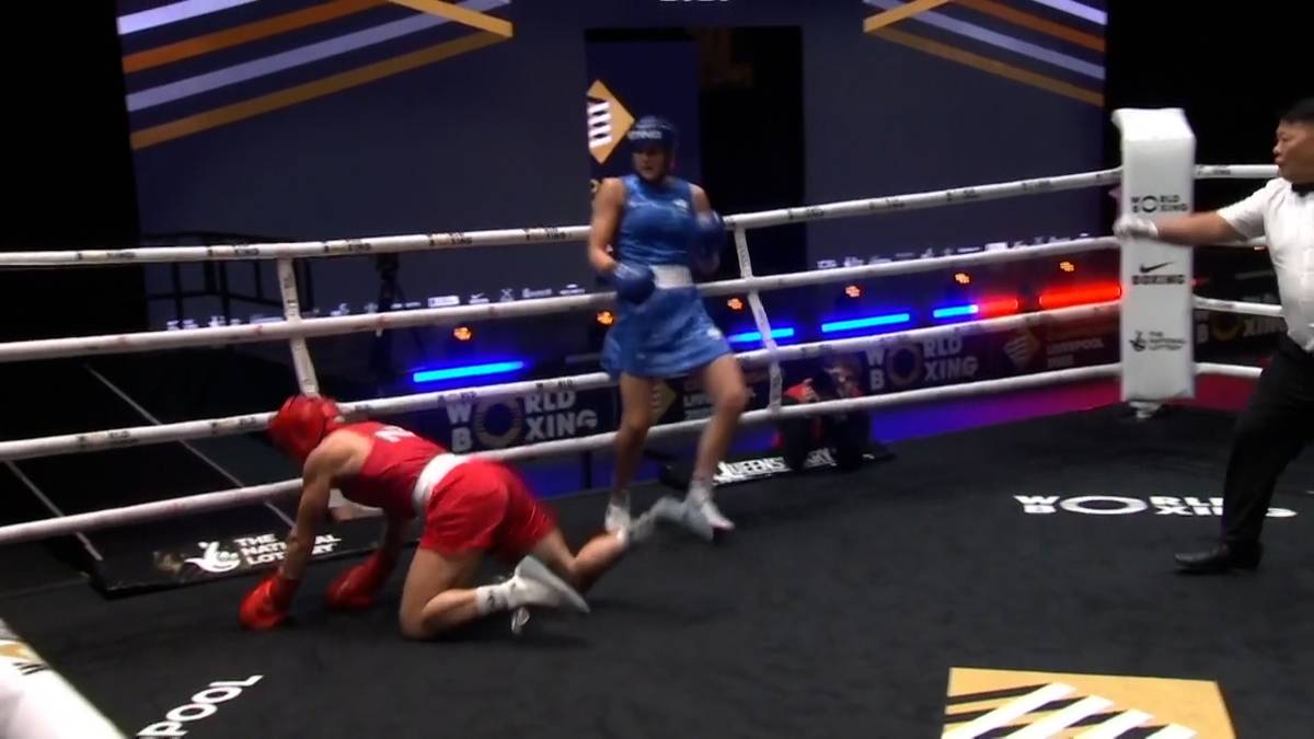 Zawodniczka boksu w niebieskim stroju, która właśnie powaliła przeciwniczkę, unosi ręce w geście triumfu. Przeciwniczka leży na macie ringu.