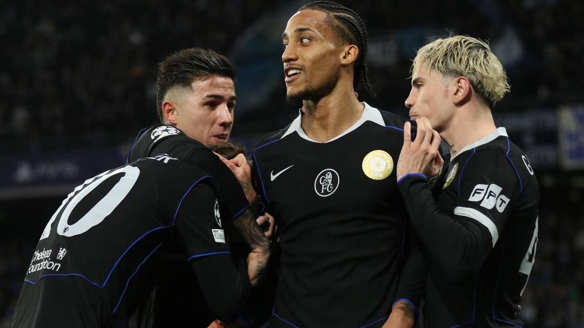 Trzech piłkarzy w czarnych strojach z białymi elementami, otaczają się nawzajem.