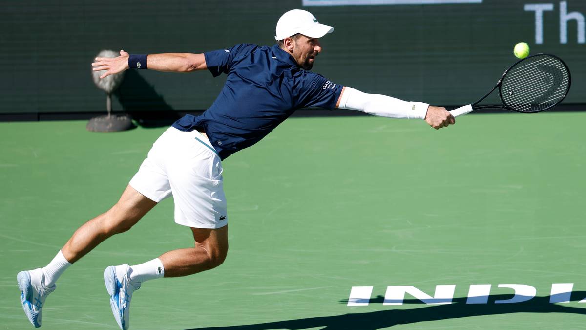 Novak Djoković w ruchu na korcie tenisowym, wykonujący bekhend.