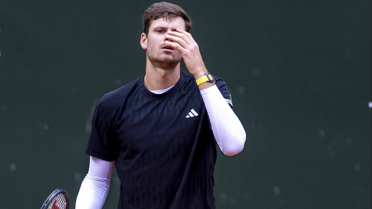 Tenisista Hubert Hurkacz w czarnej koszulce sportowej, zakrywa twarz dłonią.