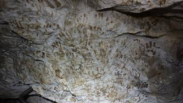 Ściany Jaskini Mroźnej pokryte licznymi śladami ludzkich dłoni i napisami wykonanymi błotem.