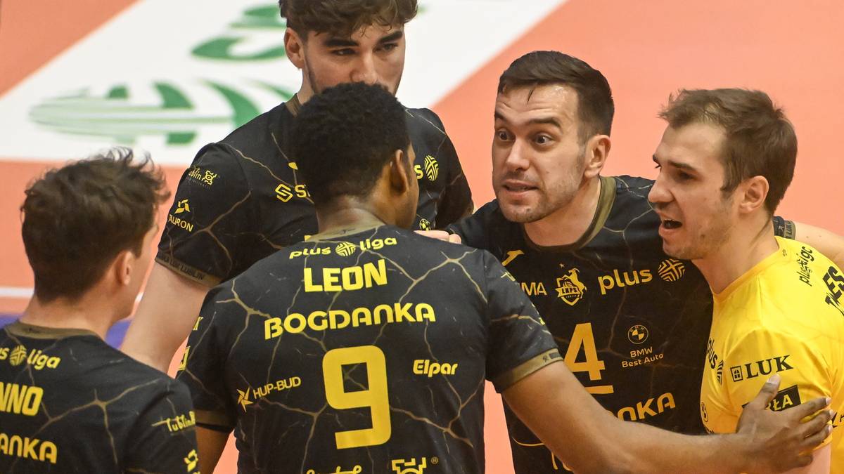 Siatkarze w strojach sportowych rozmawiają ze sobą na boisku.