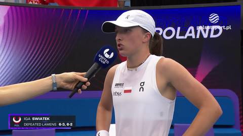 Iga Świątek w białej czapce i białym topie z logo ON stoi przed mikrofonem, udzielając wywiadu. W tle widoczny jest ekran z napisem POLAND.
