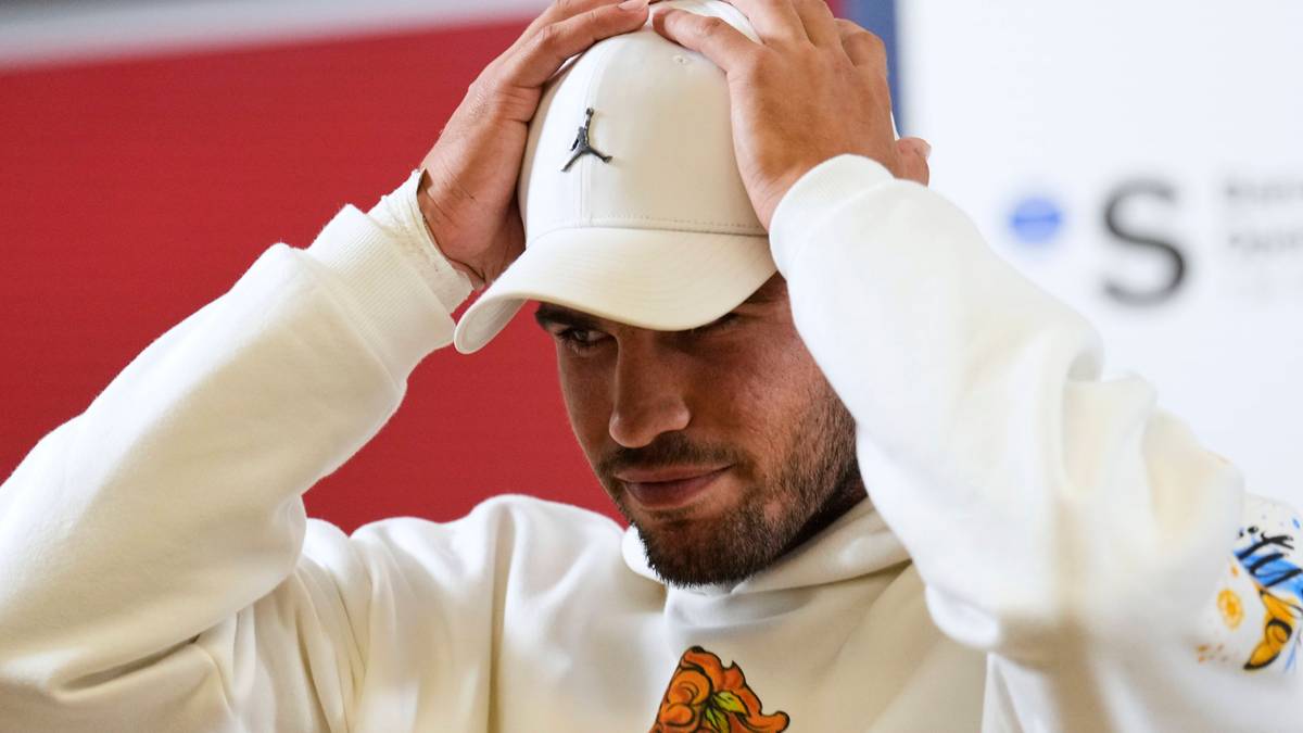 Carlos Alcaraz zakłada na głowę białą czapkę z daszkiem z logo Jumpman.