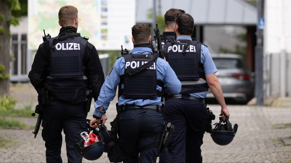 Policjanci w kamizelkach z napisem POLIZEI idą w kierunku widza.