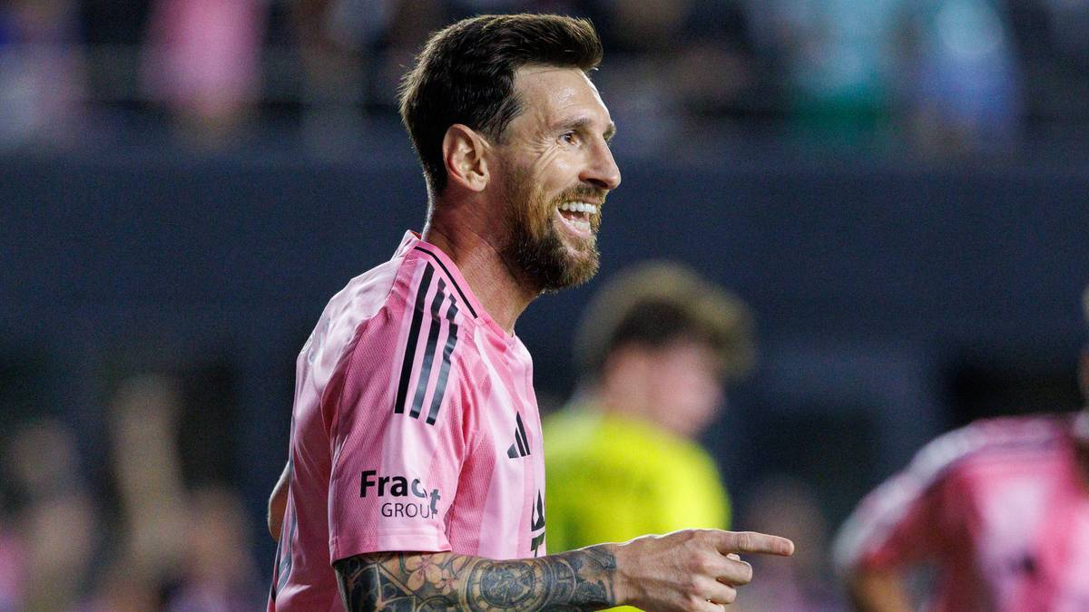 Lionel Messi w różowej koszulce piłkarskiej, uśmiechnięty i wskazujący palcem