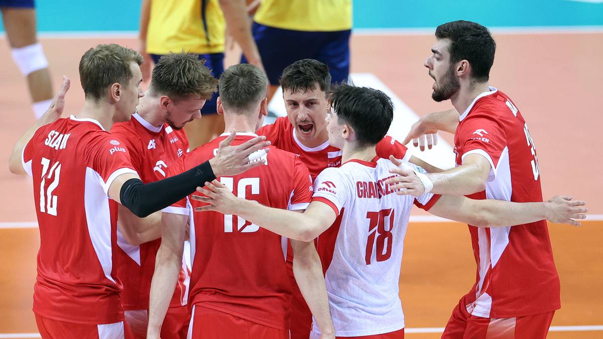 Drużyna siatkarzy w czerwonych strojach świętuje zwycięstwo w meczu, przytulając się i ściskając dłonie.