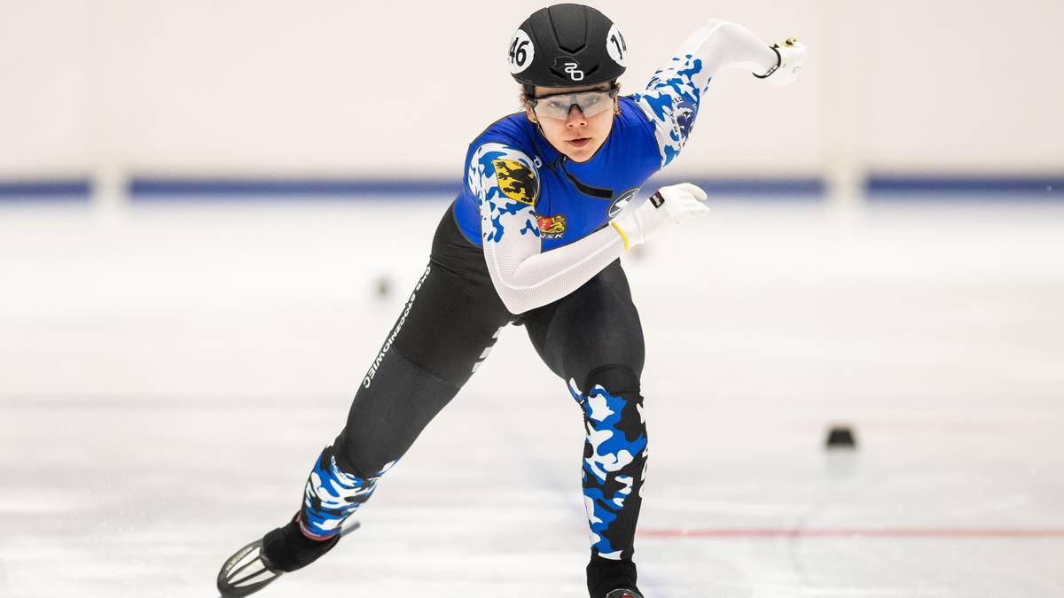 Zawodniczka short tracku w niebiesko-białym stroju podczas wyścigu na lodzie.