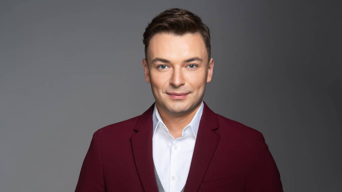 Eugeniusz Diaczkow w garniturze w kolorze burgunda, białą koszulą i szarą kamizelką.