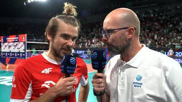 Jakub Popiwczak w czerwonej koszulce siatkarskiej udziela wywiadu dziennikarzczo
