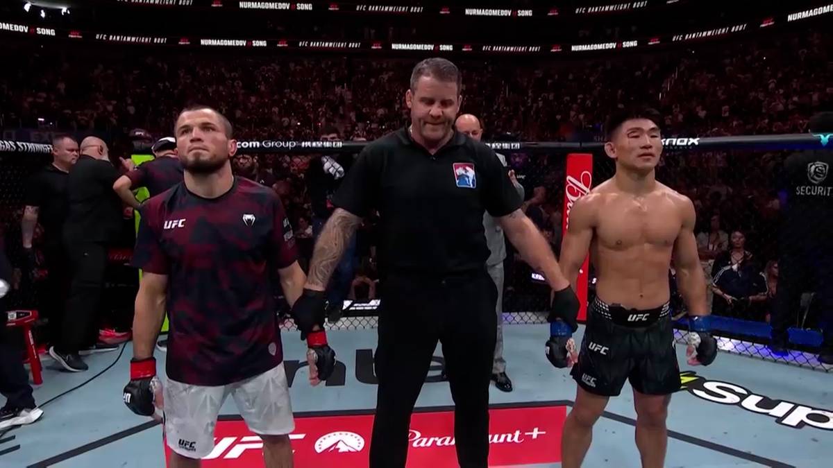 Sędzia MMA stoi pomiędzy dwoma zawodnikami, trzymając ich za ręce przed walką.