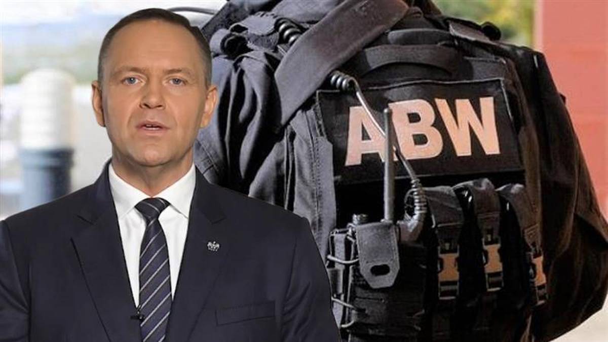 Mężczyzna w garniturze stoi obok kamizelki taktycznej z napisem "ABW"