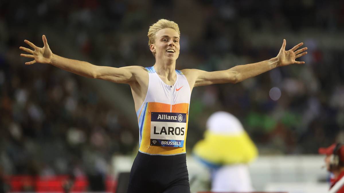 Młody lekkoatleta w sportowym stroju z uniesionymi rękami świętuje zwycięstwo.